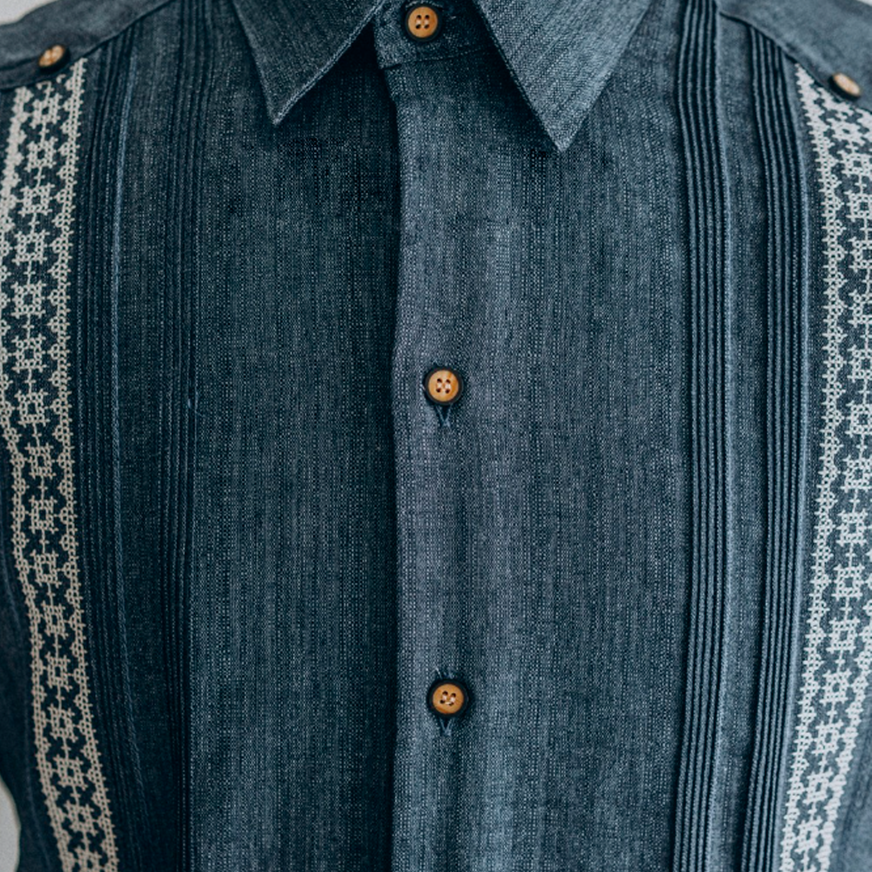 Close-up of handmade white embroidery on dark blue guayabera