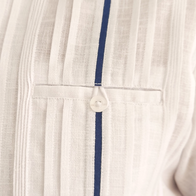 Close-up of navy blue trim on luxury white long-sleeve wedding guayabera
