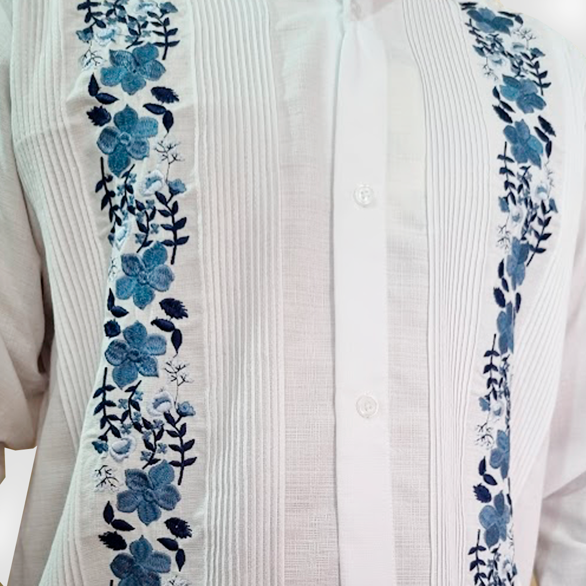 Detailed view of blue floral embroidery on white guayabera