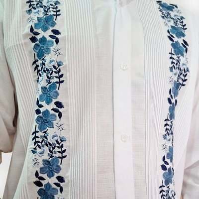 Detailed view of blue floral embroidery on white guayabera